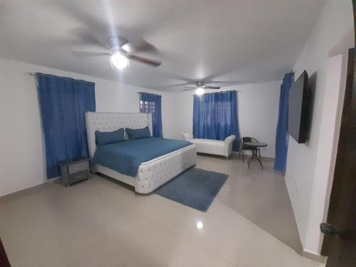 1 dormitorio con cama azul y cortinas azules en BRISTOL HOME VILLA! Residencial Naime 3 en San Pedro de Macorís