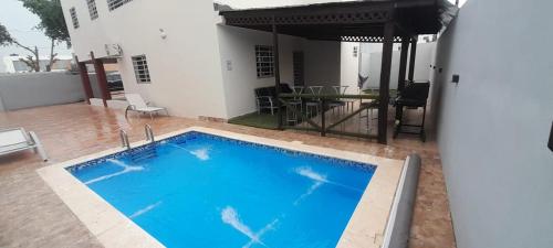 una gran piscina con una mesa y una casa en BRISTOL HOME VILLA! Residencial Naime 3 en San Pedro de Macorís