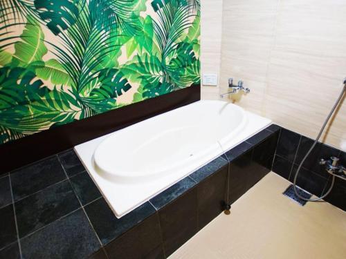 W łazience znajduje się biała umywalka i tropikalna tapeta. w obiekcie Hotel Firstwood 大栄店 w mieście Narita