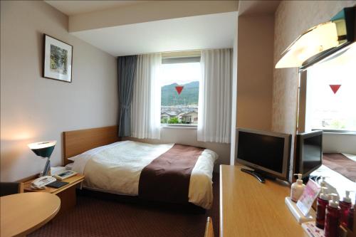 a hotel room with a bed and a television at 国家公務員共済組合連合会びわこ保養所（KKRホテルびわこ） in Otsu