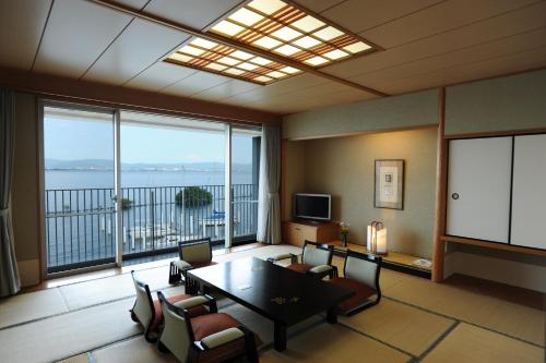 a living room with a table and chairs and a large window at 国家公務員共済組合連合会びわこ保養所（KKRホテルびわこ） in Otsu