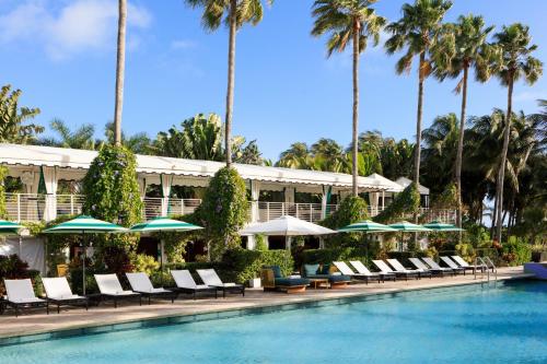 una piscina presso il resort con sedie e ombrelloni di Kimpton Surfcomber Hotel, an IHG Hotel a Miami Beach