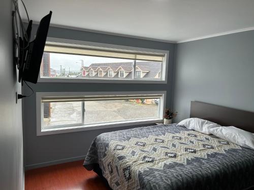 1 dormitorio con cama y ventana grande en Hostal Esesur, en Puerto Montt