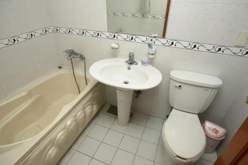 a bathroom with a toilet and a sink and a tub at Jun Motel in Jeju