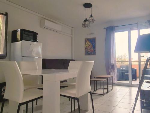 une cuisine et une salle à manger avec une table et des chaises blanches dans l'établissement T2 avec Terrasse, Parking à Collioure - FR-1-309-420, à Collioure