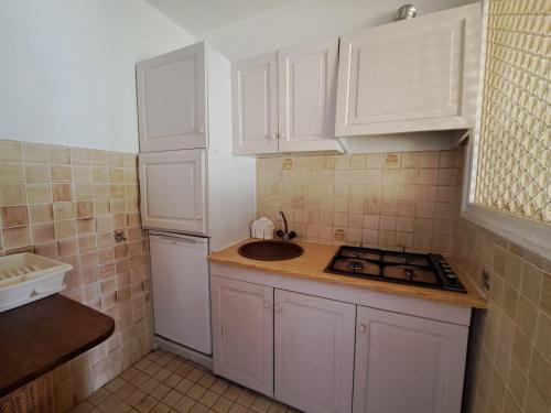 une petite cuisine avec des armoires blanches et un évier dans l'établissement Appartement spacieux avec belle terrasse, proche pistes et commerces de Pra Loup 1600 - FR-1-165A-188, à Uvernet