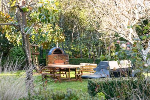 a picnic table and a grill in a garden at Azidene House & Spa Apartment in Daylesford