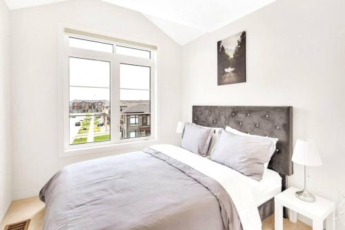 Un dormitorio blanco con una cama grande y una ventana en Tulip Smartments Brampton-Spacious 4 Bedroom Near Airport, en Brampton