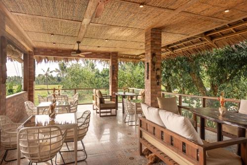 un patio al aire libre con mesas y sillas y techo de madera. en The Hillside Resort Siargao en General Luna