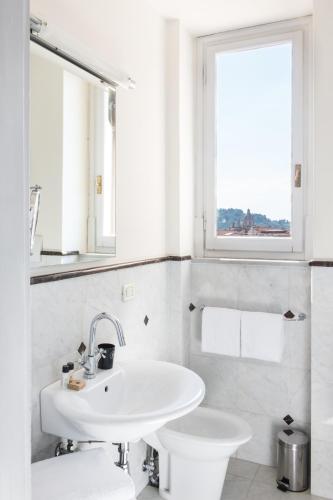 a white bathroom with a sink and a toilet at Tornabuoni Suites Collection Residenza D'Epoca in Florence