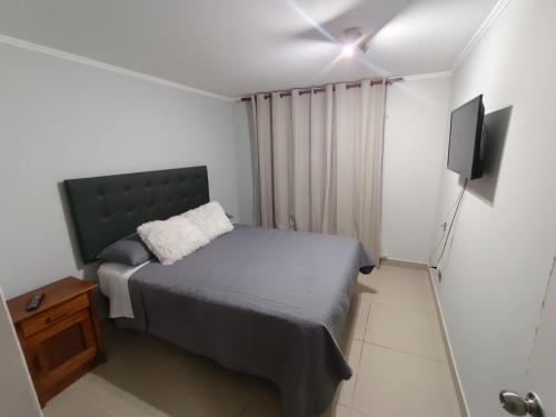 a bedroom with a bed and a flat screen tv at Departamento Condominio Arica in Arica