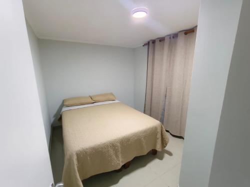 a small bed in a white room with a window at Departamento Condominio Arica in Arica