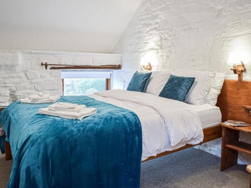 a bedroom with a large bed with a blue blanket at Y Beudy - Uk46191 in Llanybydder