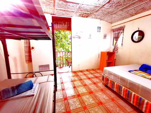a bedroom with two beds and a door to a balcony at Stay N Save B&B in Oslob