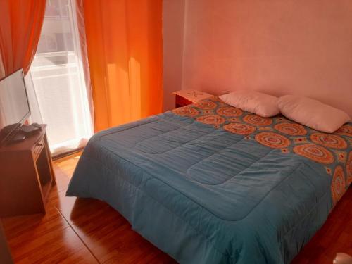 1 dormitorio con 1 cama azul y pared de color naranja en Departamento verano la serena, en La Serena