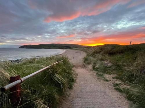 a dirt road leading to the beach at sunset at Inishroel Cottage in Campbeltown