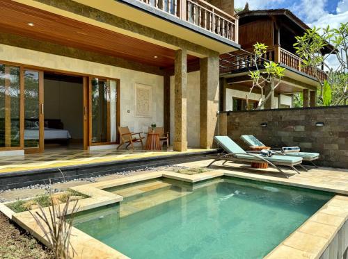 a swimming pool with two chairs and a house at Abian Ayu Villa in Sidemen