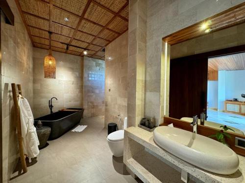 a bathroom with a sink and a toilet and a tub at Abian Ayu Villa in Sidemen