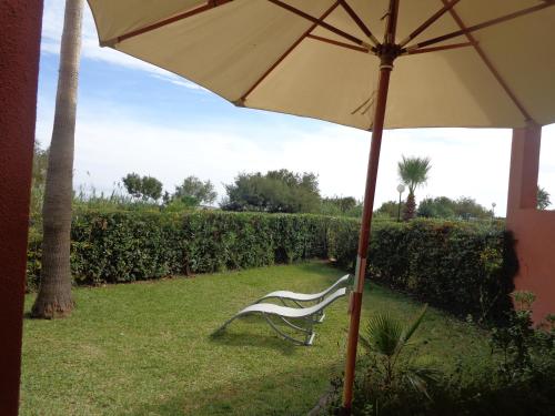 a white chair sitting under an umbrella in the grass at Manilva Beach 140 in Manilva