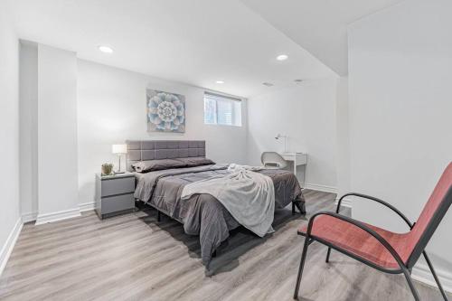 a white bedroom with a bed and a chair at Cozy Haven Retreat 2Bed Basement in Whitby