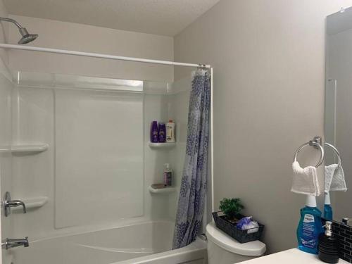 Un baño blanco con ducha y WC. en Guest Suite with Queen Bed -Home Away from Home, en Regina