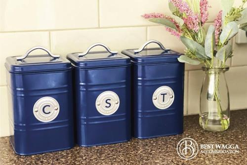 three blue trash cans sitting next to a vase with flowers at Suburban Bliss - Elegant Villa 1 in Wagga Wagga