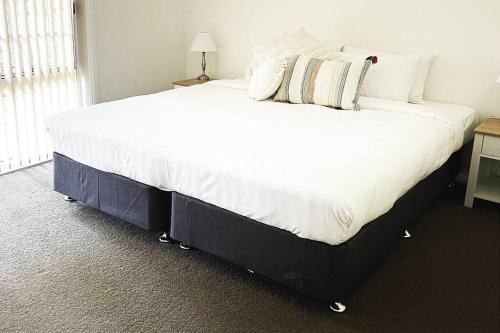 a bedroom with a large bed with white sheets and pillows at Suburban Bliss - Elegant Villa 1 in Wagga Wagga