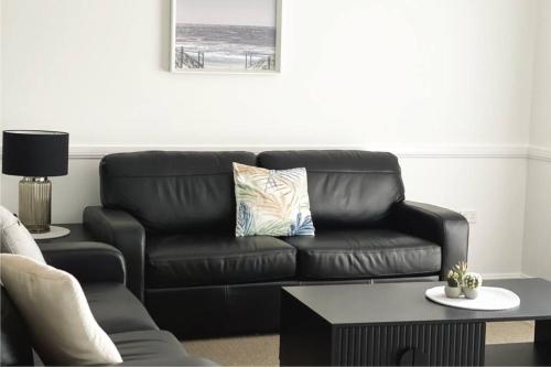 a black leather couch in a living room with a table at Suburban Bliss - Elegant Villa 1 in Wagga Wagga