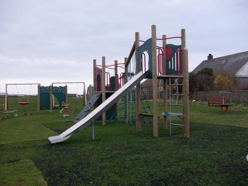 a playground with a slide in the grass at Inishroel Cottage in Campbeltown