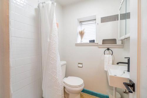 a white bathroom with a toilet and a sink at Riverside Luxe: Stylish Designer Retreat in Reno