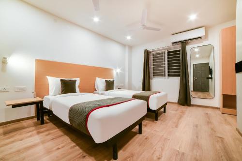a hotel room with two beds and a mirror at Townhouse Sarjapur Near Bellandur in Bengaluru