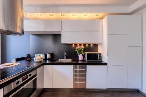une cuisine avec des armoires blanches et un comptoir noir dans l'établissement Heart of Cannes Amazing design apartment Croisette Top Location Best Seller by OIam Properties, à Cannes
