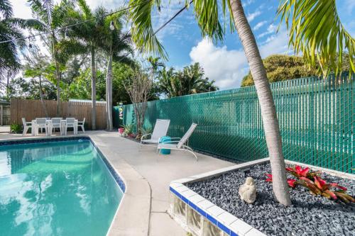 a swimming pool with a palm tree in a yard at Paradise Oasis with Heated Pool 8 mins from the Beach! in Pompano Beach