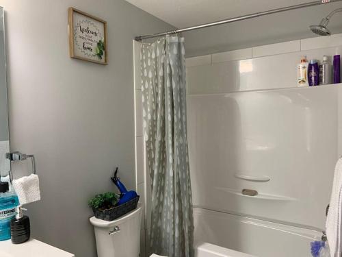 a bathroom with a shower curtain and a toilet at Guest Suite in Regina - Feels like home in Regina