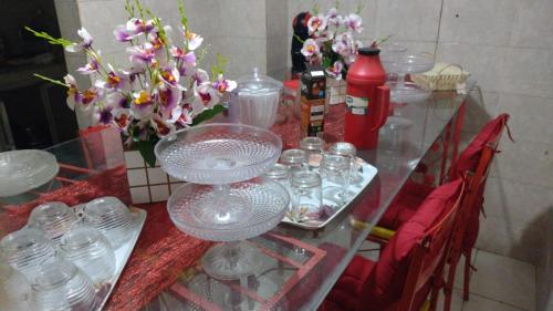 リオデジャネイロにあるOlympio Houseのガラス瓶と花束付きのガラステーブル