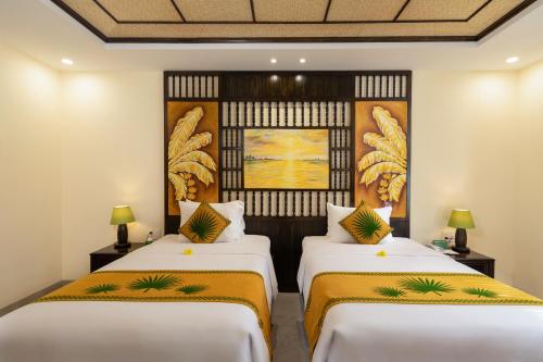 two beds in a room with white walls at Palm Garden Beach Resort & Spa in Hoi An