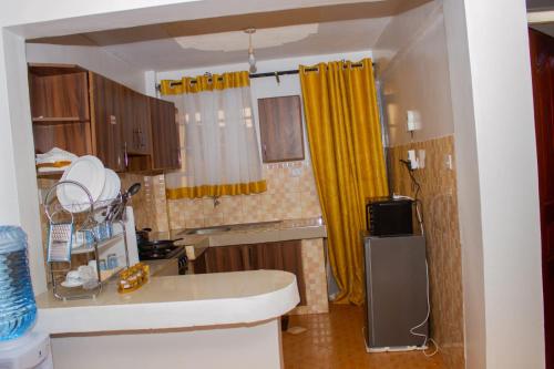 uma pequena cozinha com cortinas amarelas e um lavatório em Decii homes em Ruaka