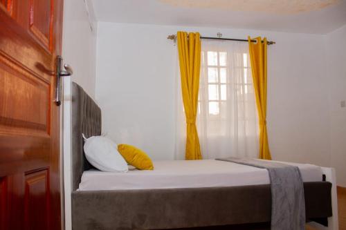 a bedroom with a bed with two pillows and a window at Decii homes in Ruaka