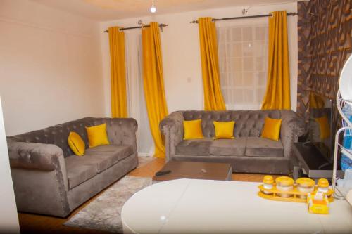 a living room with two couches and yellow curtains at Decii homes in Ruaka