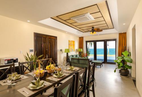 a dining room with a table and chairs and the ocean at Palm Garden Beach Resort & Spa in Hoi An