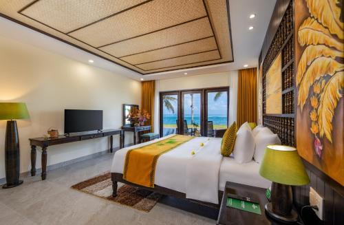 a bedroom with a bed with a view of the ocean at Palm Garden Beach Resort & Spa in Hoi An