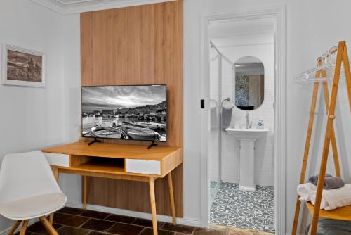 a room with a desk with a tv on a wall at Mapleton Park Cottage in Springwood