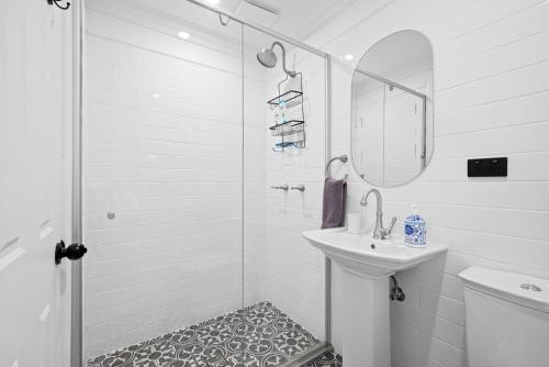 baño blanco con ducha y lavamanos en Mapleton Park Cottage en Springwood