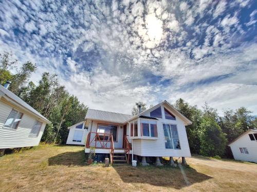 a white house with a porch on a field at Cabañas Bosquemar 1 in Queilén