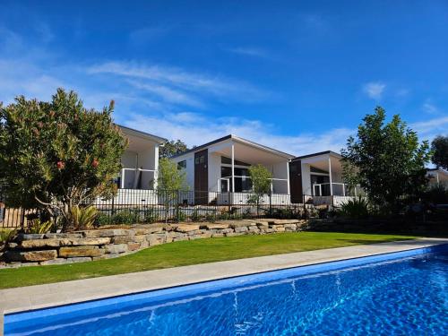 a house with a swimming pool in front of a house at Murray Bridge Tourist Park in Murray Bridge