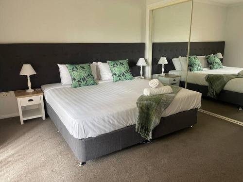 a bedroom with two beds with mirrors and lamps at Suburban Bliss - Elegant Villa 2 in Wagga Wagga