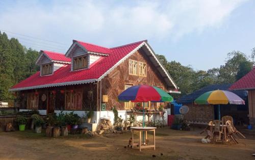 a house with a red roof and two umbrellas at Megitar Homestay by StayApart in Bijanbāri Bāzār