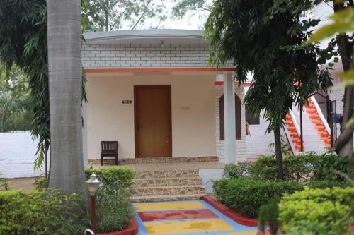 a small white house with a door and a tree at OYO HOTEL SHREE KRISHNA JUNGLE RESORT KHAJURAHO in Khajurāho