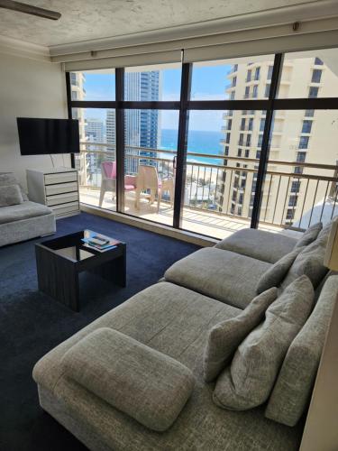 a living room with a couch and a large window at Beachcomber Resort - Official in Gold Coast