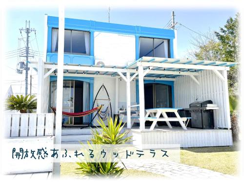 uma casa branca e azul com um alpendre em ビーチハウス at ワニベース em Otsu